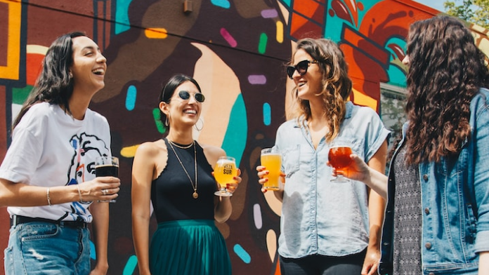 four women smiling and drinking beer